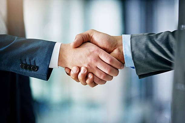 Closeup shot of two businessmen shaking hands in an office kontakt til kontrakt